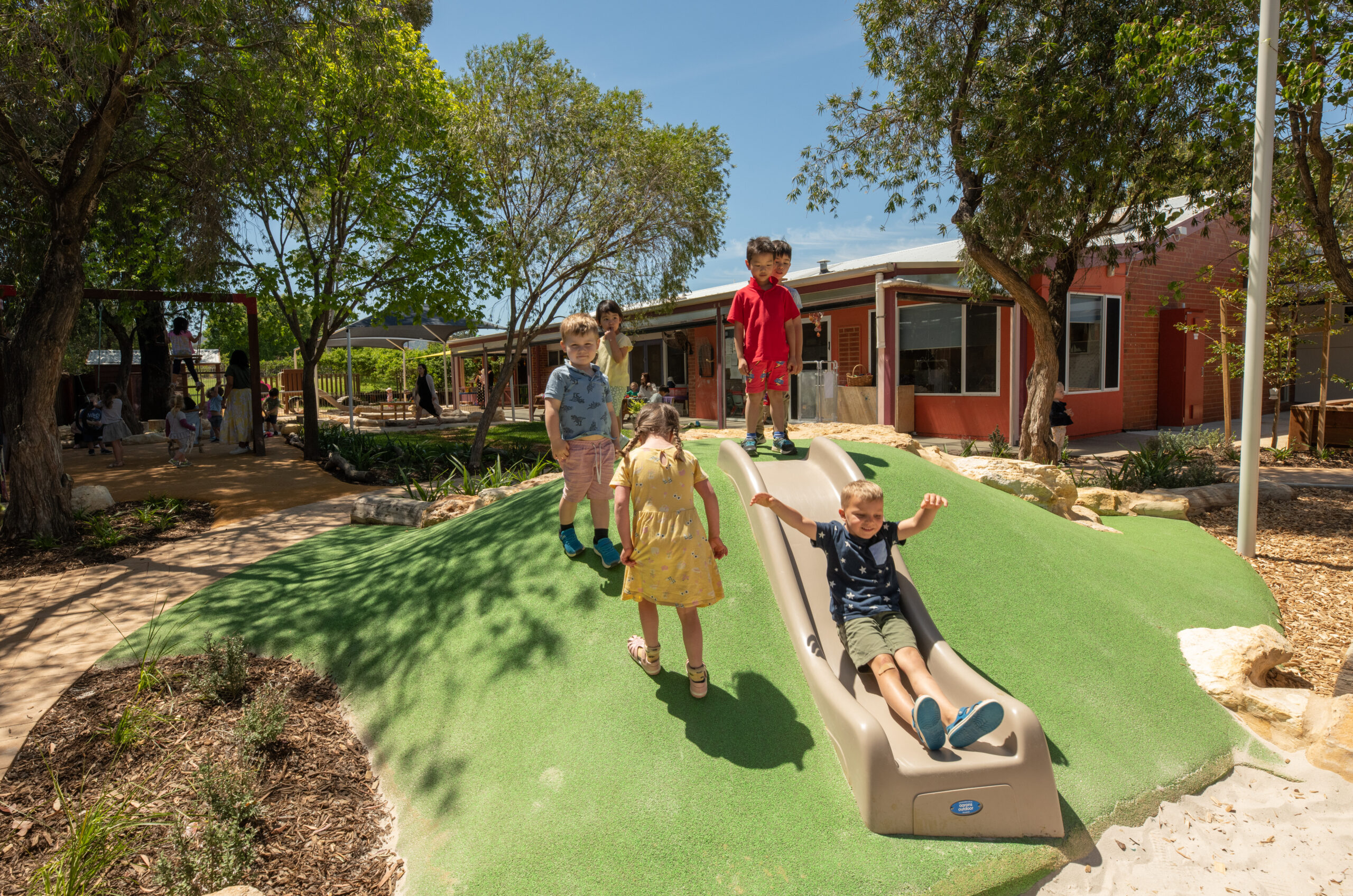 Children playing on the new slide and soft mound