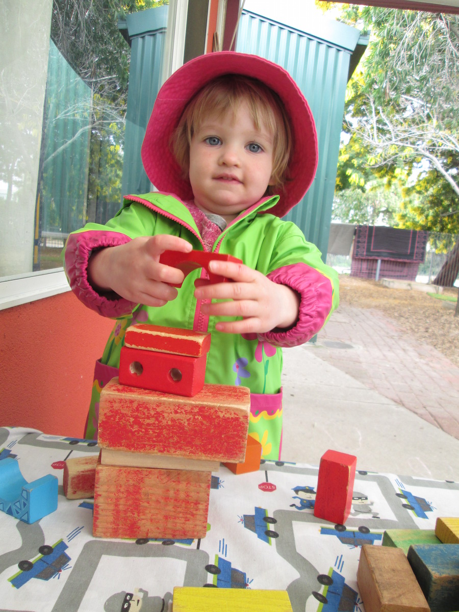 Junior kindy aged girl playing with wooden blocks