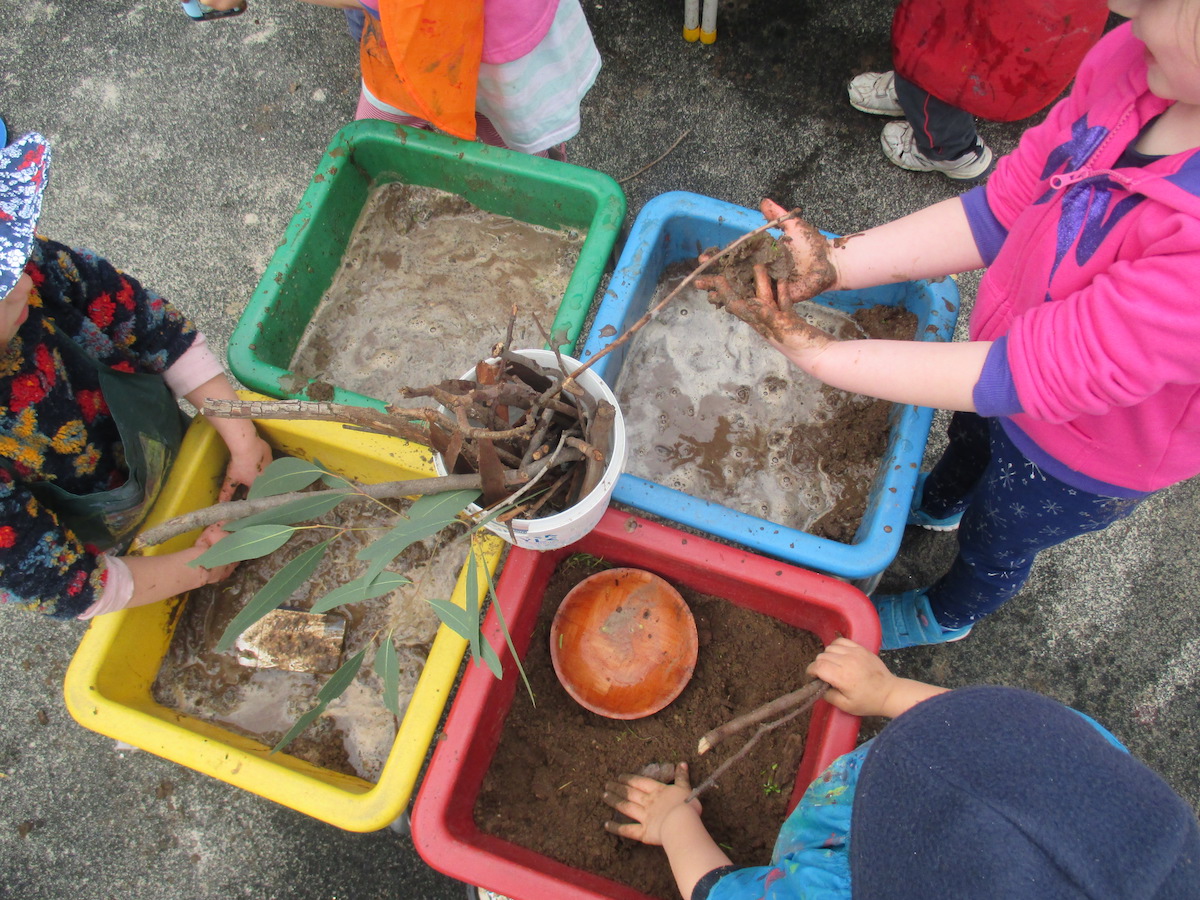 Junior kindy kids enjoying mud play with soil, water and sticks